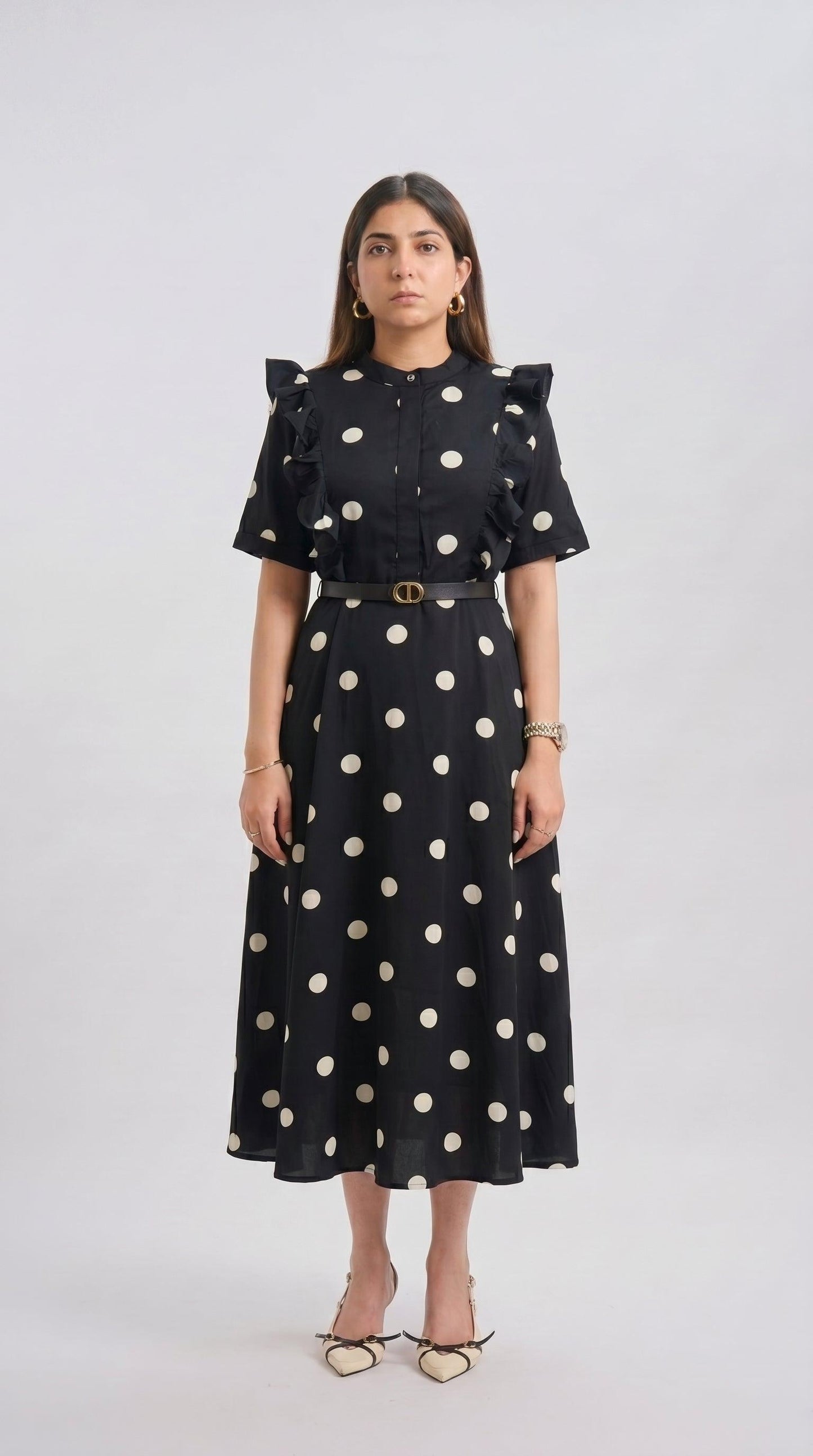 Woman wearing a black dress with white polka dots on a white background