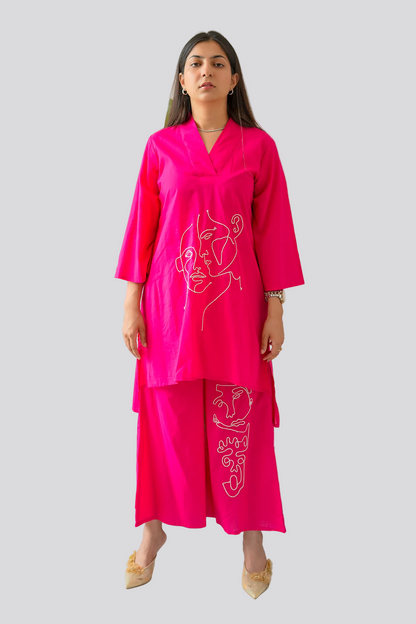 Woman wearing a bright pink dress with white designs on a plain background