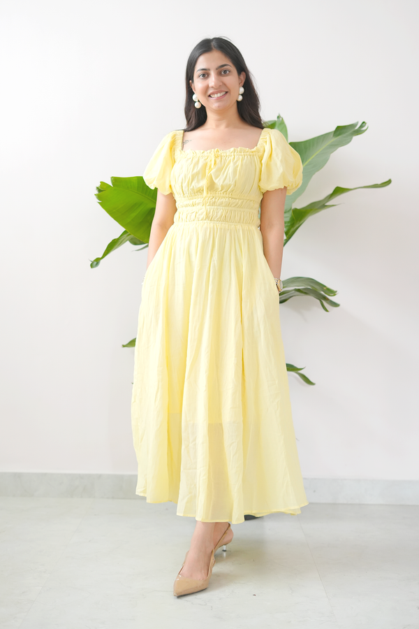 Woman wearing a yellow dress with puff sleeves against a white background