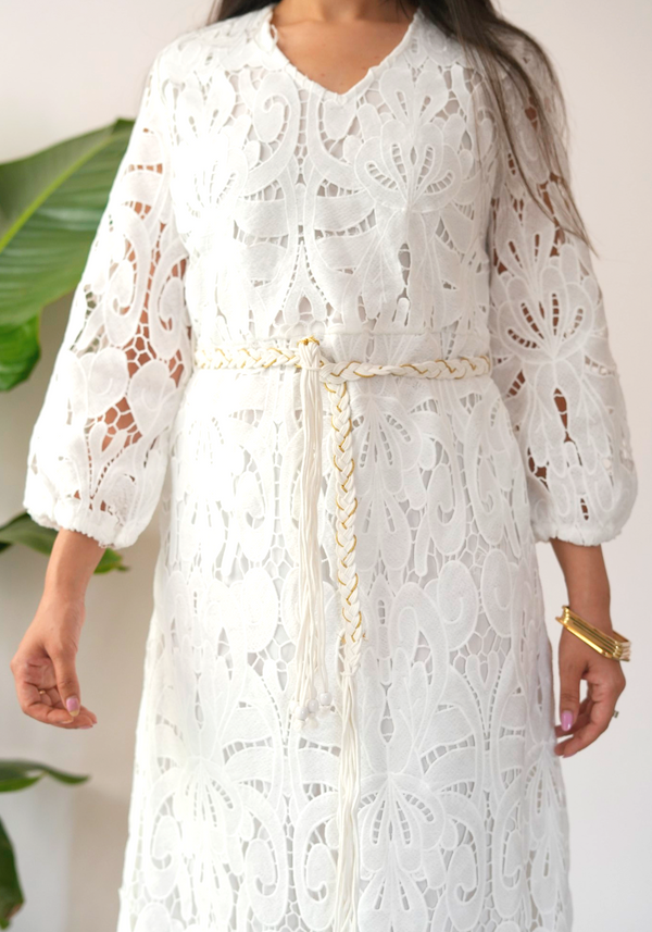 White lace dress with bell sleeves and a tie belt worn by a person.