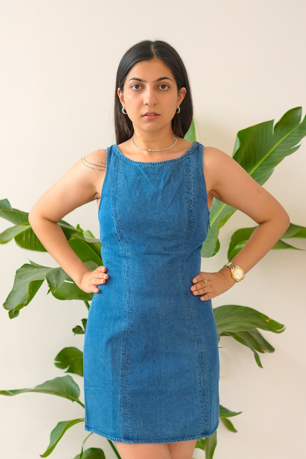 Woman wearing a blue dress standing in front of green plants