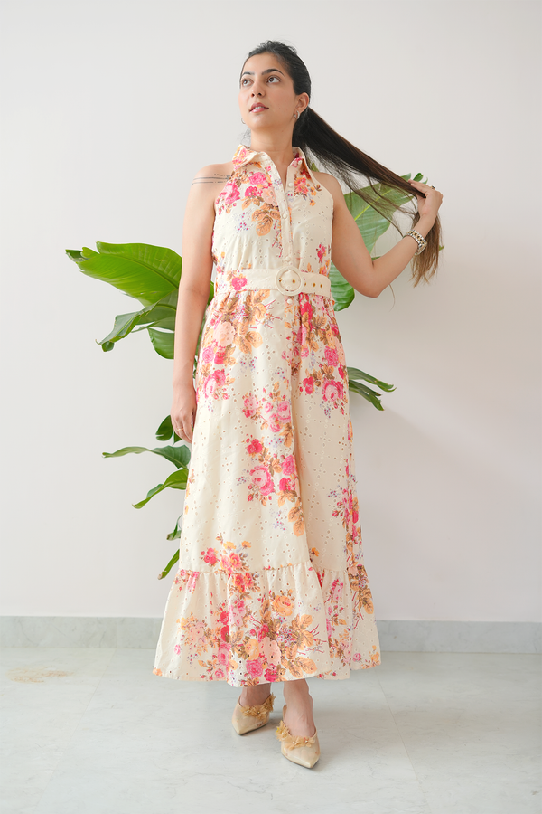 Woman wearing a floral dress standing against a white background with a plant.