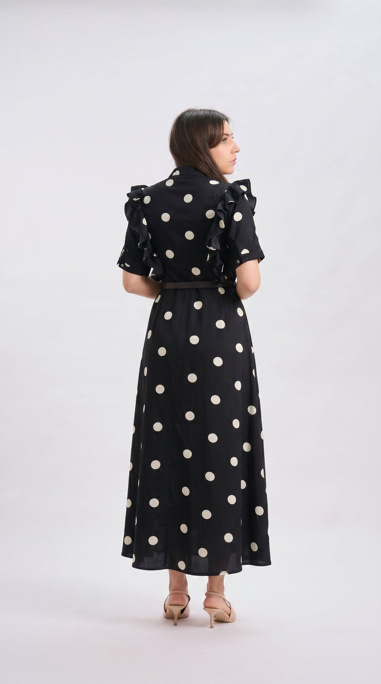 Woman wearing a black dress with white polka dots on a white background