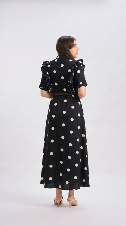 Woman wearing a black dress with white polka dots on a white background