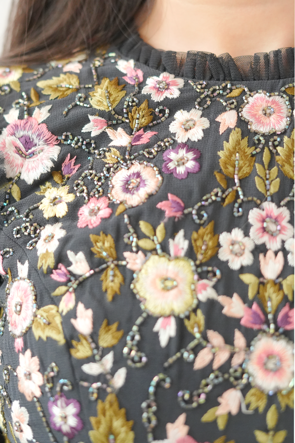 Close-up of a floral patterned fabric with pink, yellow, and green flowers on a dark background.