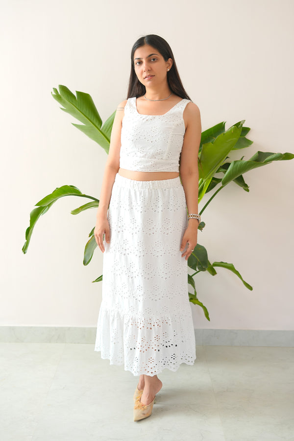 Woman wearing a white lace outfit standing in front of a plant