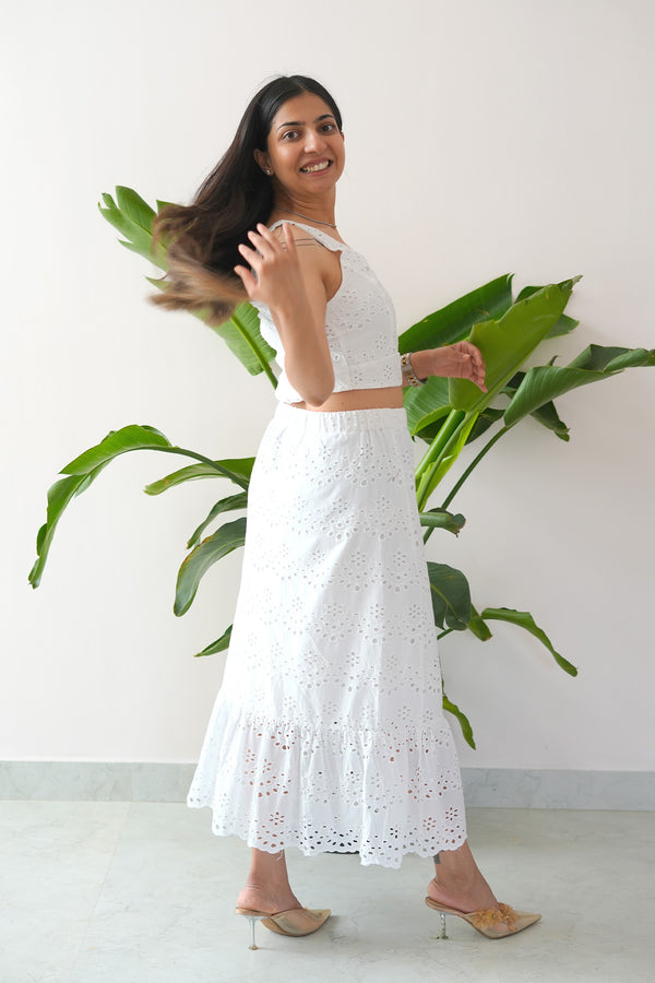 Woman in a white dress standing in front of a plant against a white wall