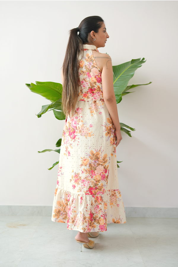Woman wearing a floral dress standing in front of a plant against a white wall