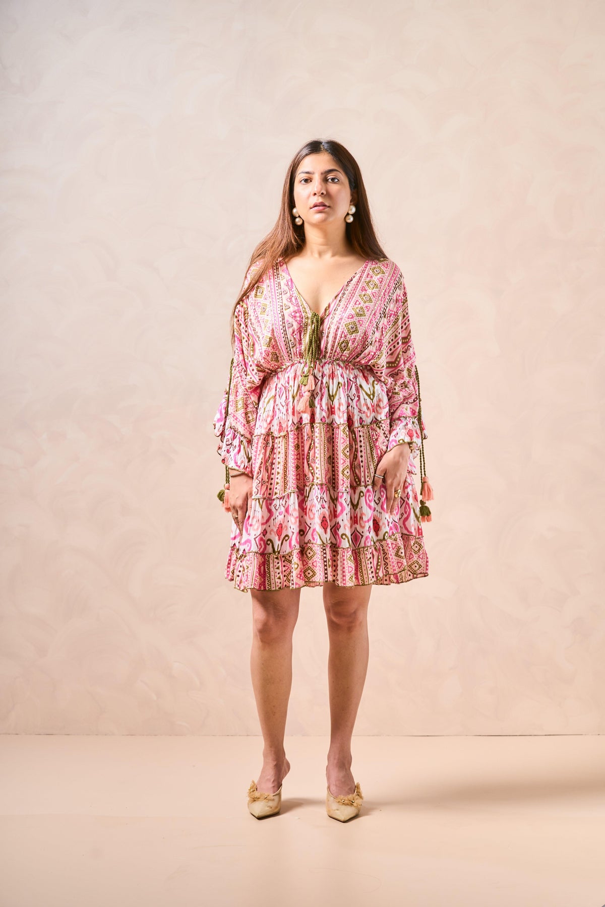 Woman wearing a pink patterned dress against a beige background