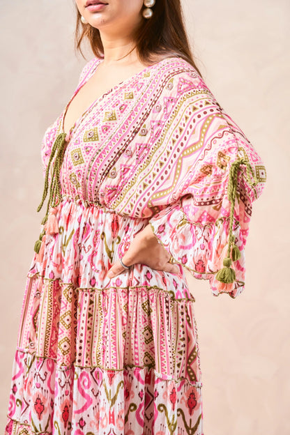 Woman wearing a pink patterned dress with tassels on a beige background