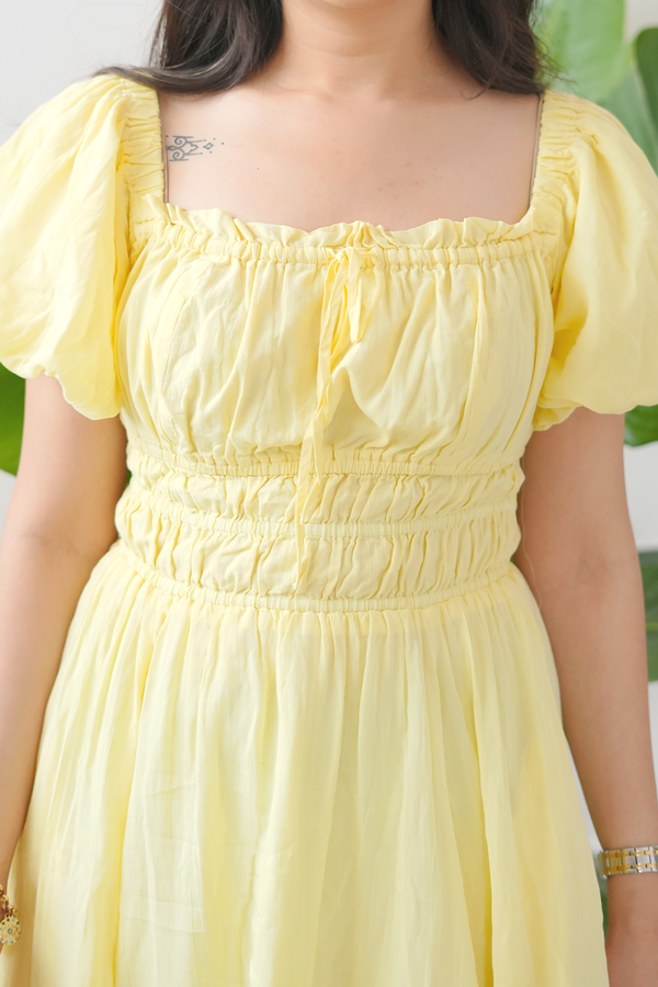 Yellow dress with puffed sleeves worn by a person, blurred background