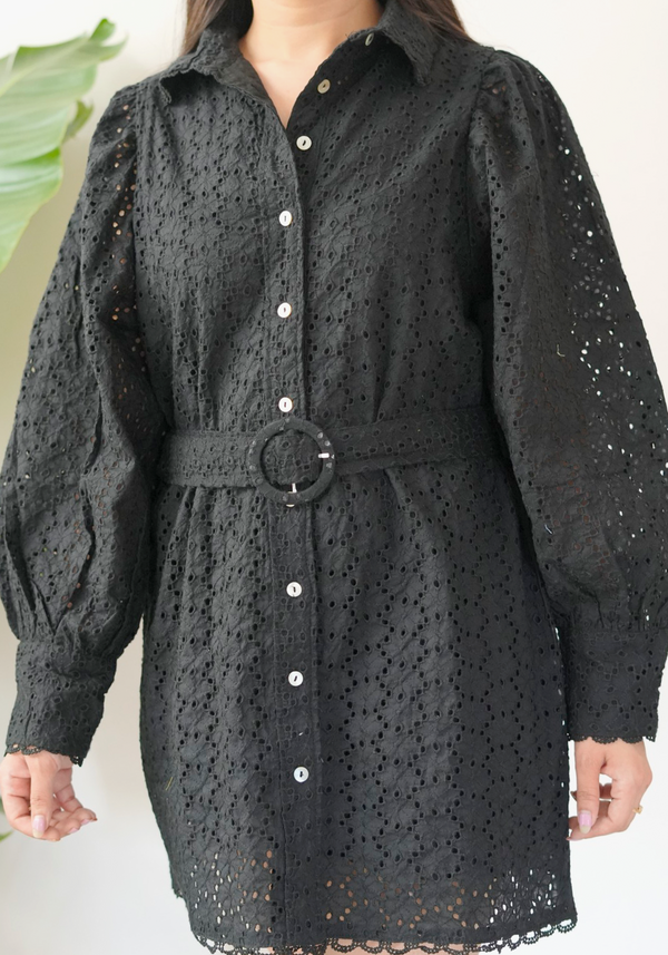 Black eyelet dress with long sleeves and a belt worn by a person.
