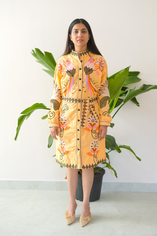 Woman wearing a patterned dress standing in front of a plant