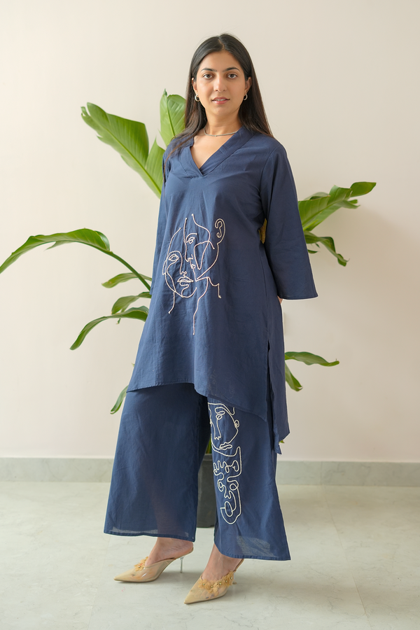 Woman wearing a blue outfit with embroidered designs in a minimalistic setting