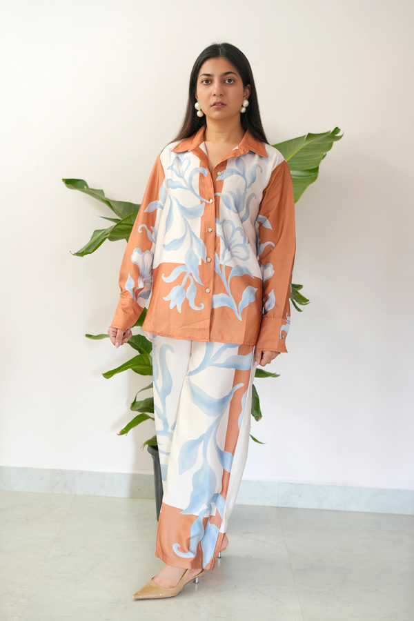 Woman wearing a floral outfit with a white background and plant decor
