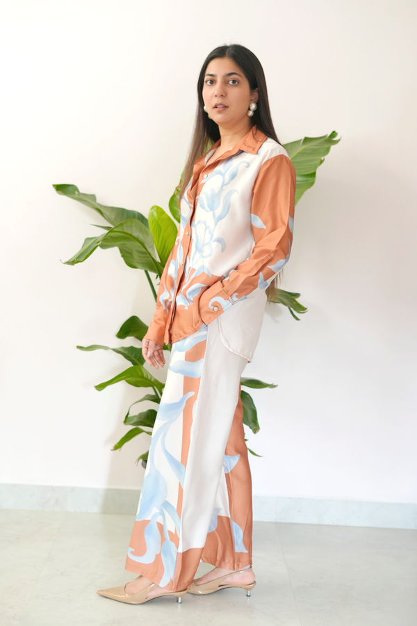 Woman wearing a patterned outfit with a plant in the background