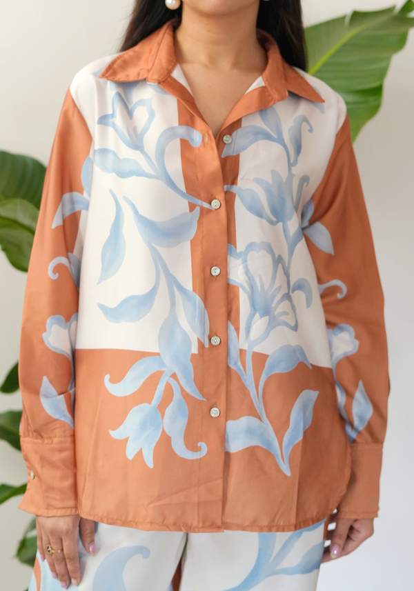 Woman wearing a floral patterned shirt with blue and peach colors.