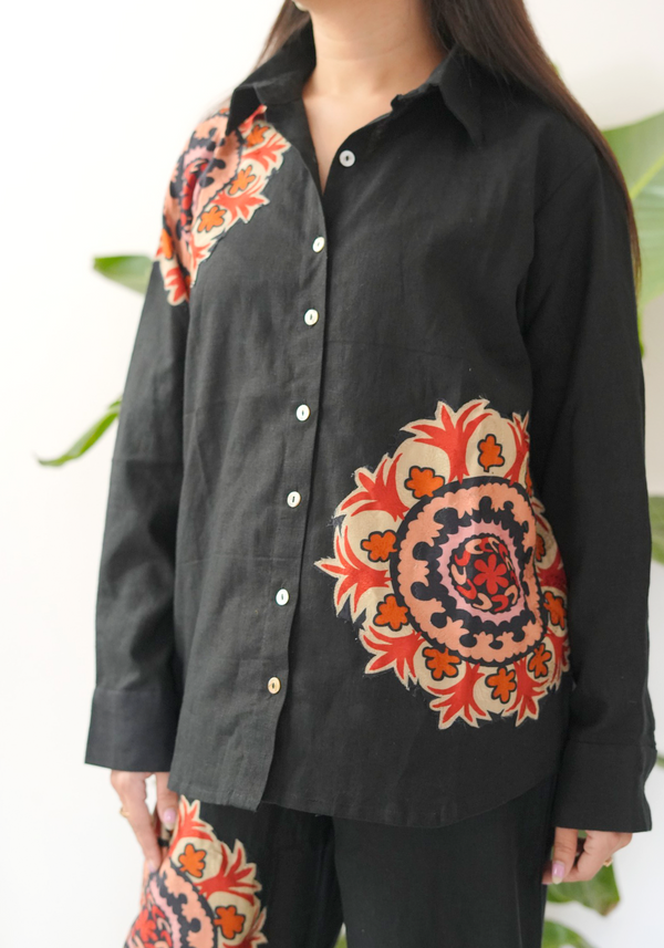 Black shirt with colorful floral patterns on the front and back.