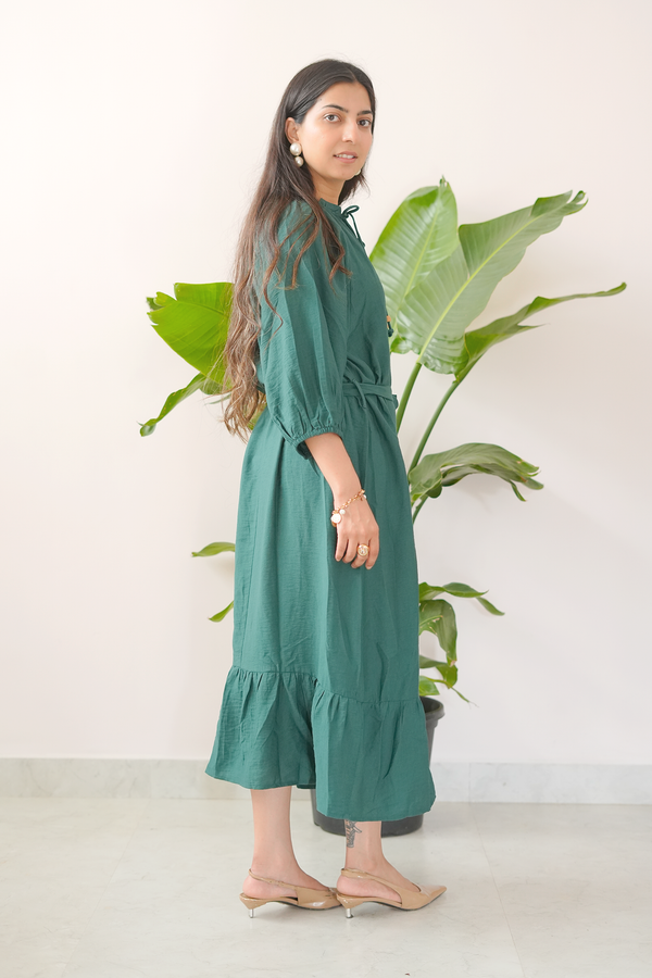 Woman wearing a green dress standing in front of a plant with a white background