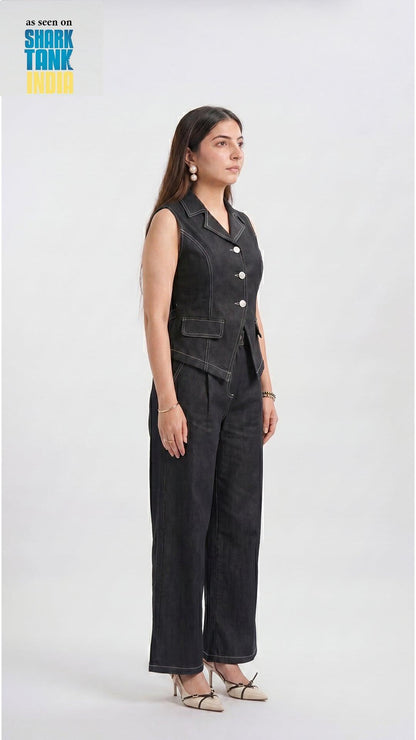 Woman wearing a black sleeveless jumpsuit with buttons on a white background, featuring 'Shark Tank' branding.