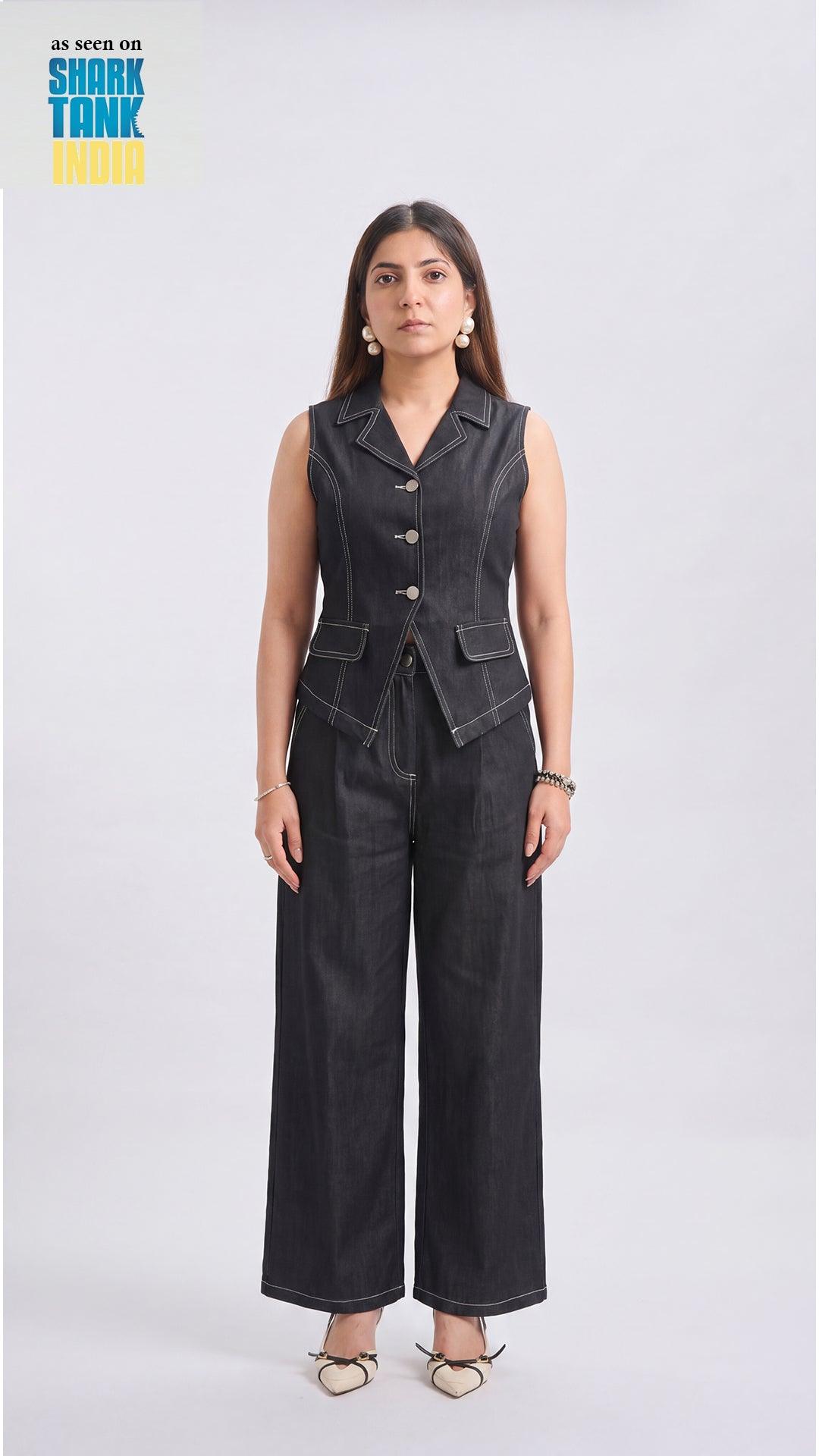 Woman wearing a black sleeveless jacket and wide-leg pants on a white background