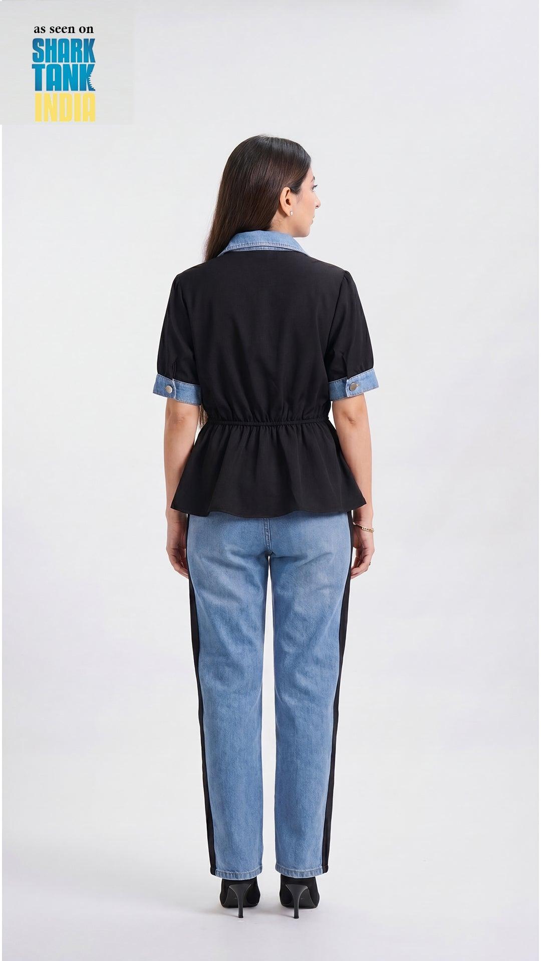 Woman wearing a black top with blue accents and blue jeans on a white background