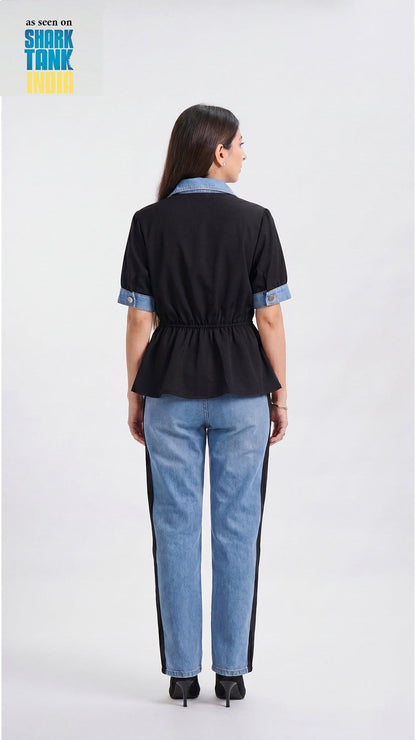 Woman wearing a black top with blue accents and blue jeans on a white background