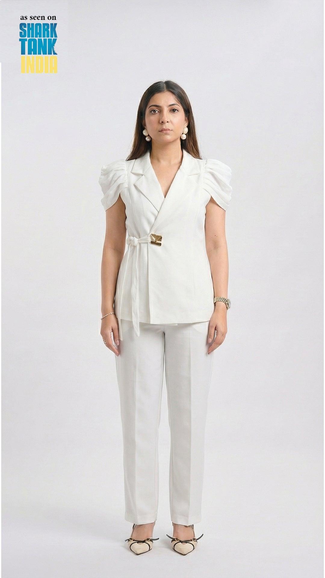 Woman wearing a white outfit with a blazer and pants on a plain background