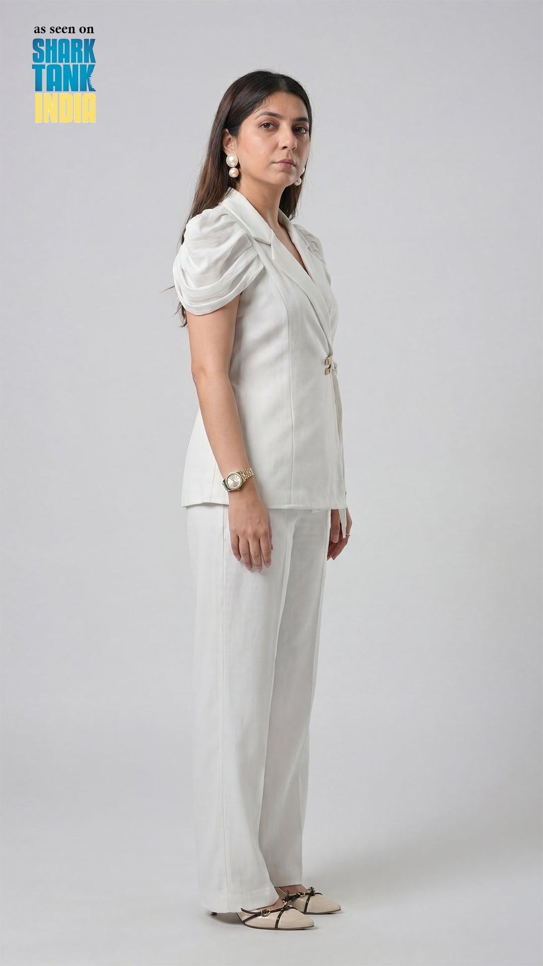 Woman in a white outfit standing against a plain background with 'Shark Tank' branding.