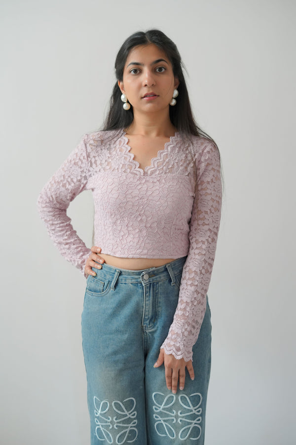 A person wearing a pink short blouse with long sleeves, featuring a heart pattern, paired with blue jeans.