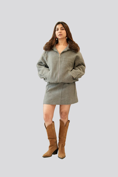 Woman wearing a green coat and brown boots on a light gray background