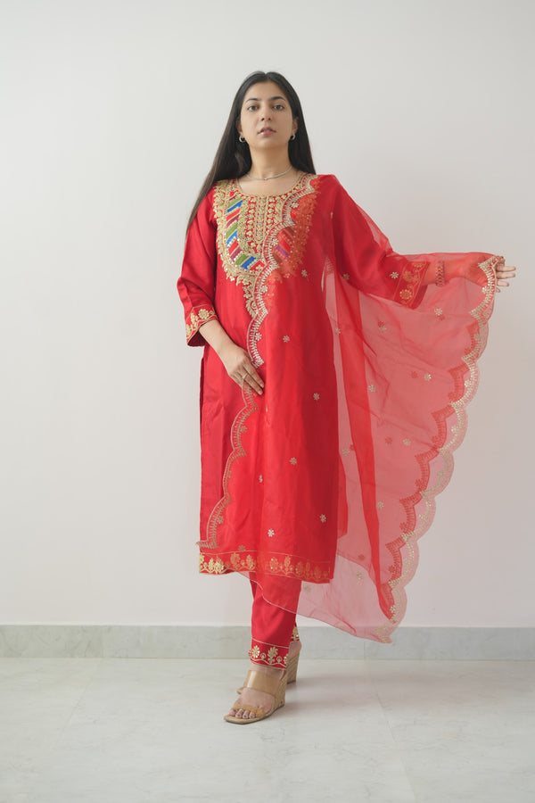 Woman wearing a red traditional outfit with gold embroidery on a white background