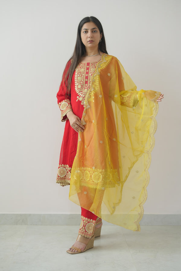 Woman wearing a yellow and red traditional outfit against a white background