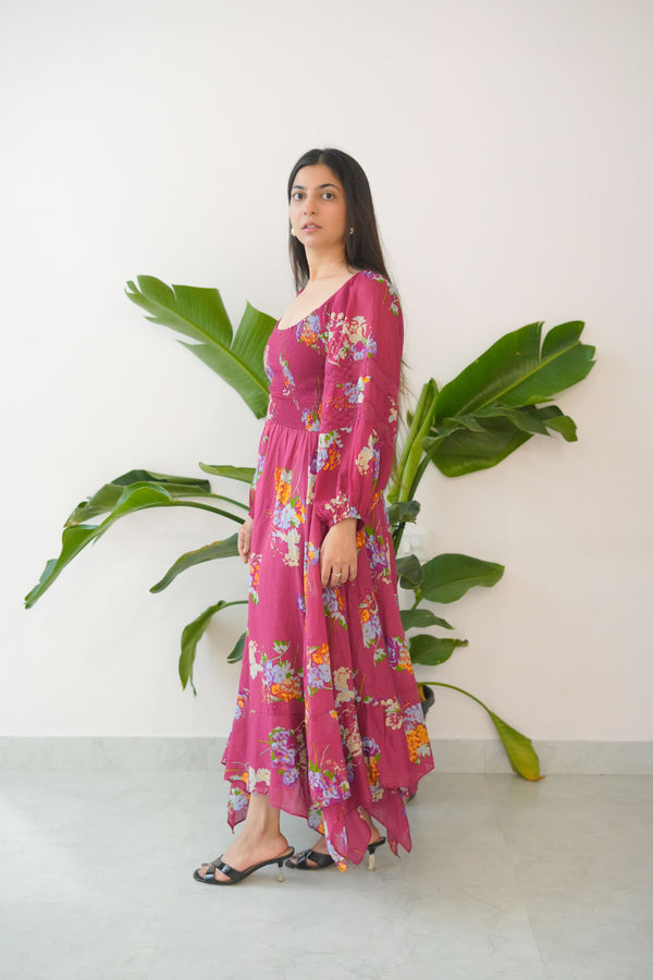 Person wearing a pink floral dress standing next to a large green plant indoors.