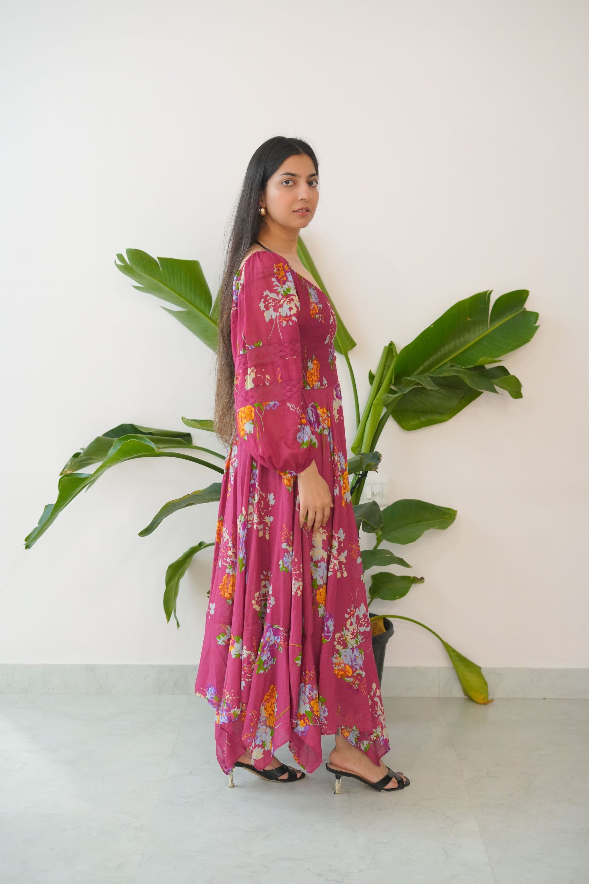 Person wearing a pink floral dress lying on a white floor with green leaves.