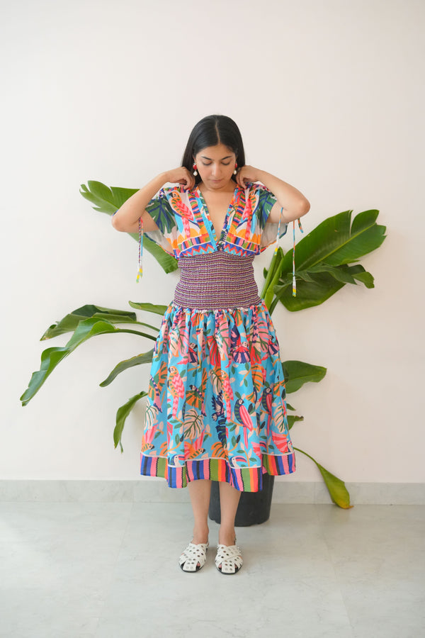 Woman in a colorful dress standing next to a potted plant on a white background