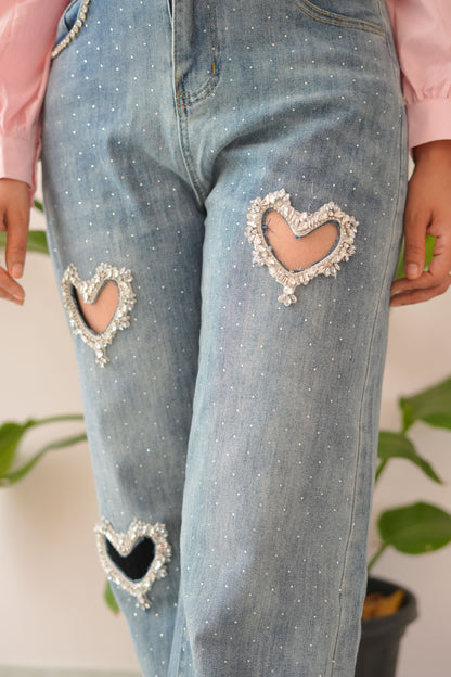 Close-up of distressed blue jeans with decorative heart patches.