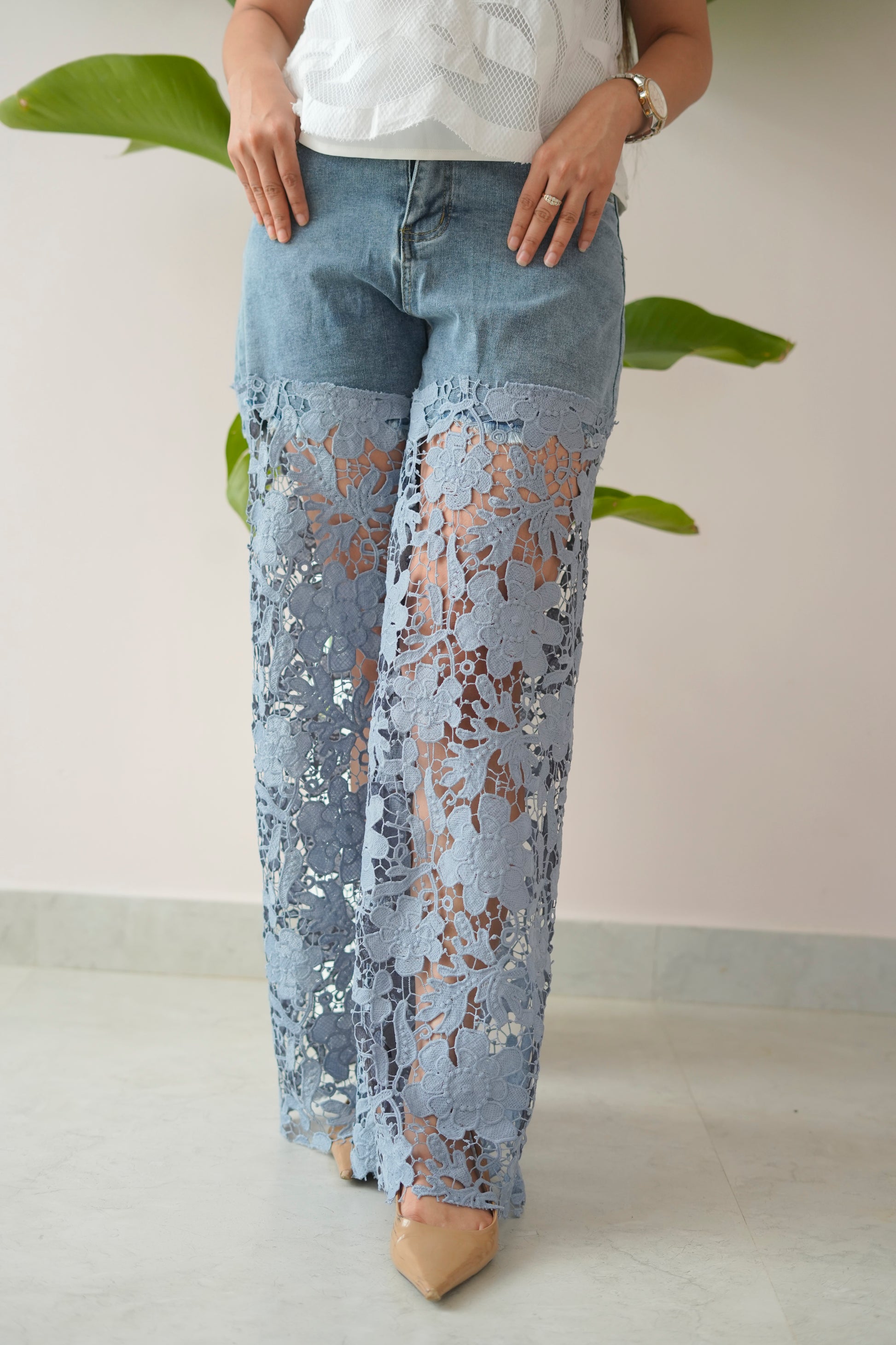 Person wearing light blue lace pants with a plain background