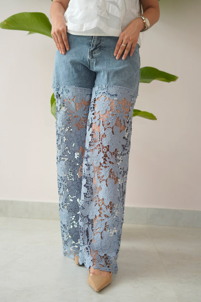 Person wearing light blue lace pants with a plain background