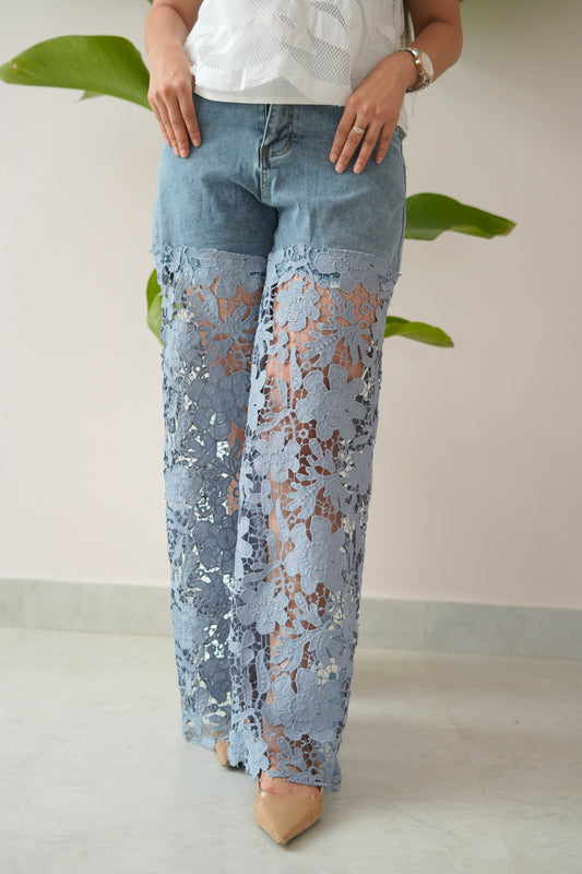 Person wearing light blue lace pants with a plain background