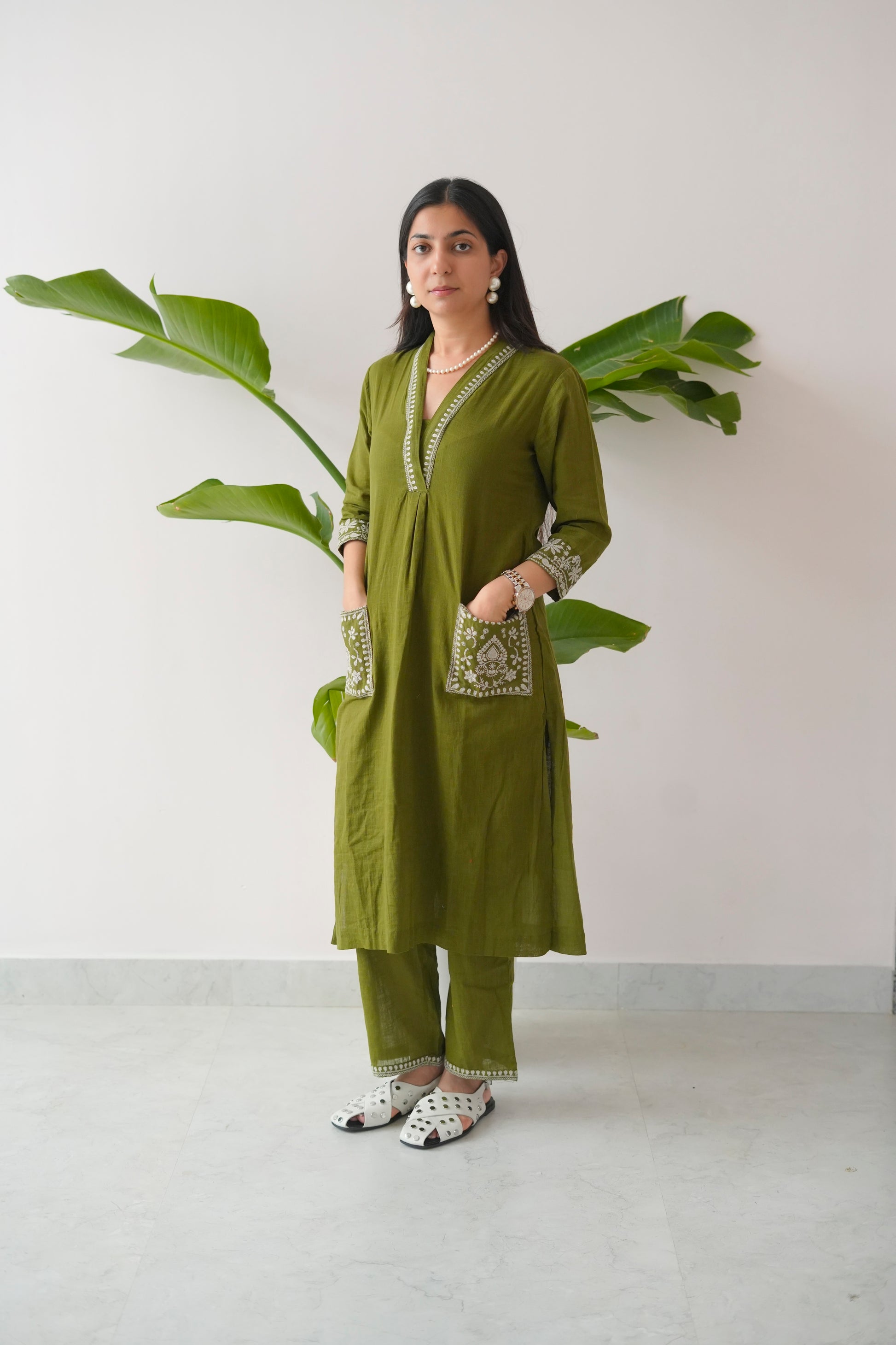 Woman wearing a green traditional outfit with a plant in the background