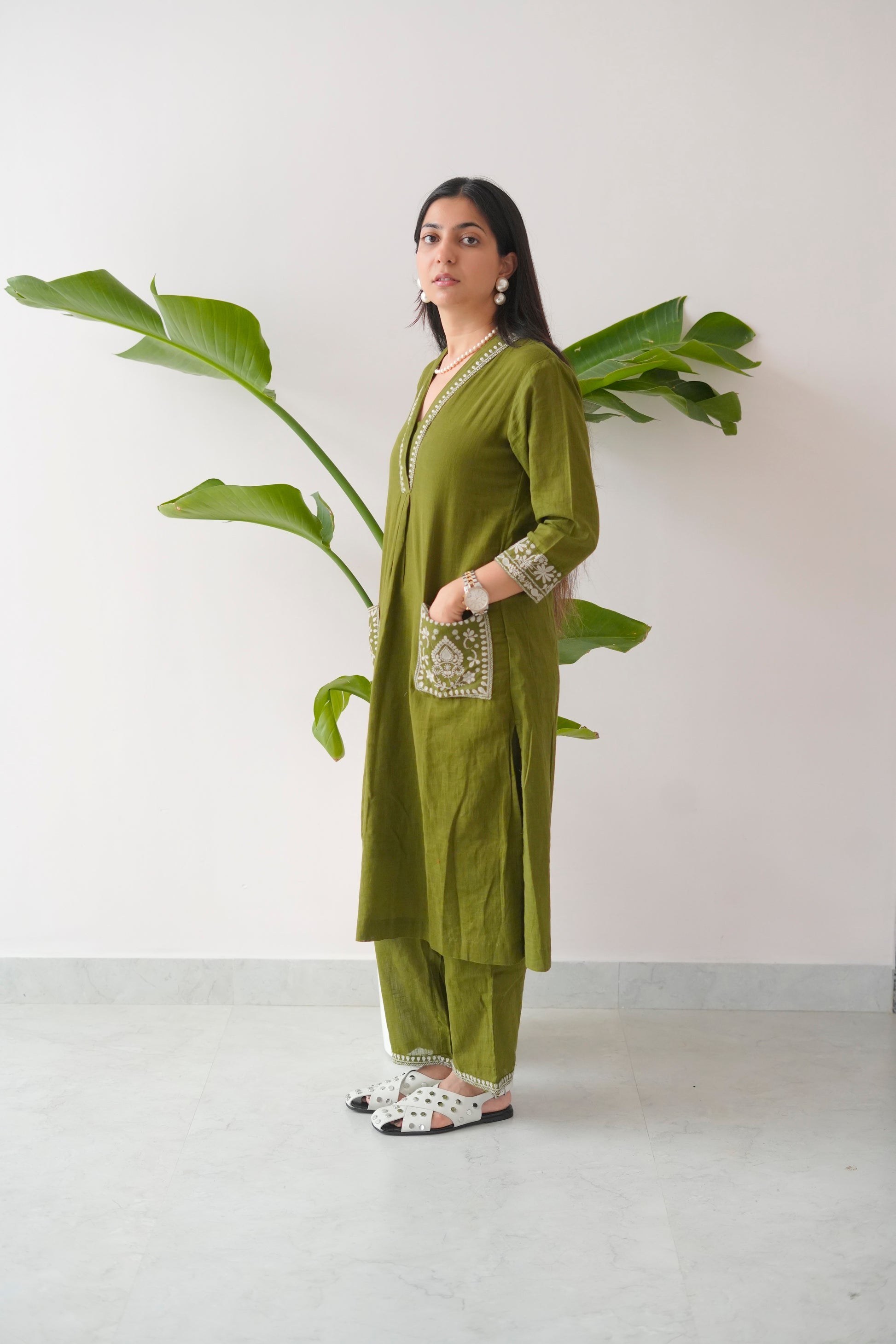 Woman wearing a green traditional outfit with a plant in the background