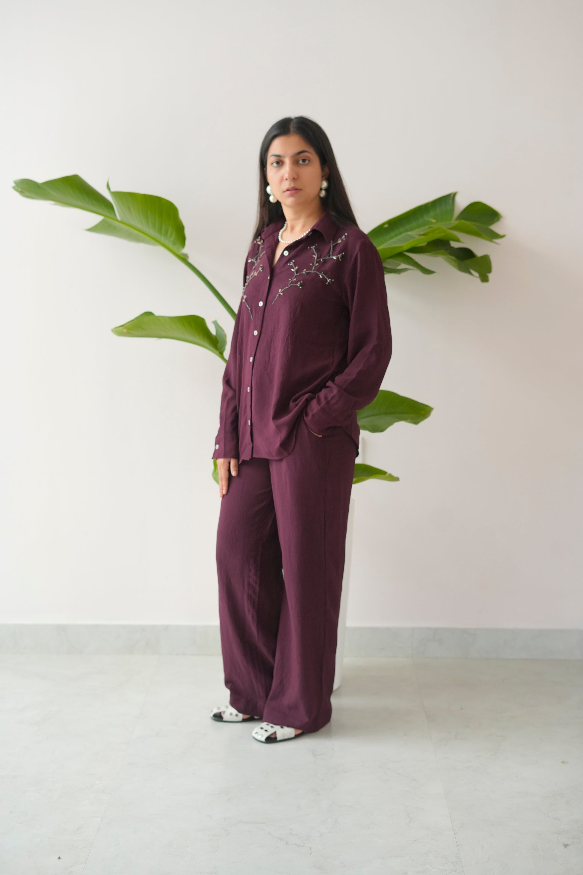 Woman wearing a purple outfit with a plant in the background