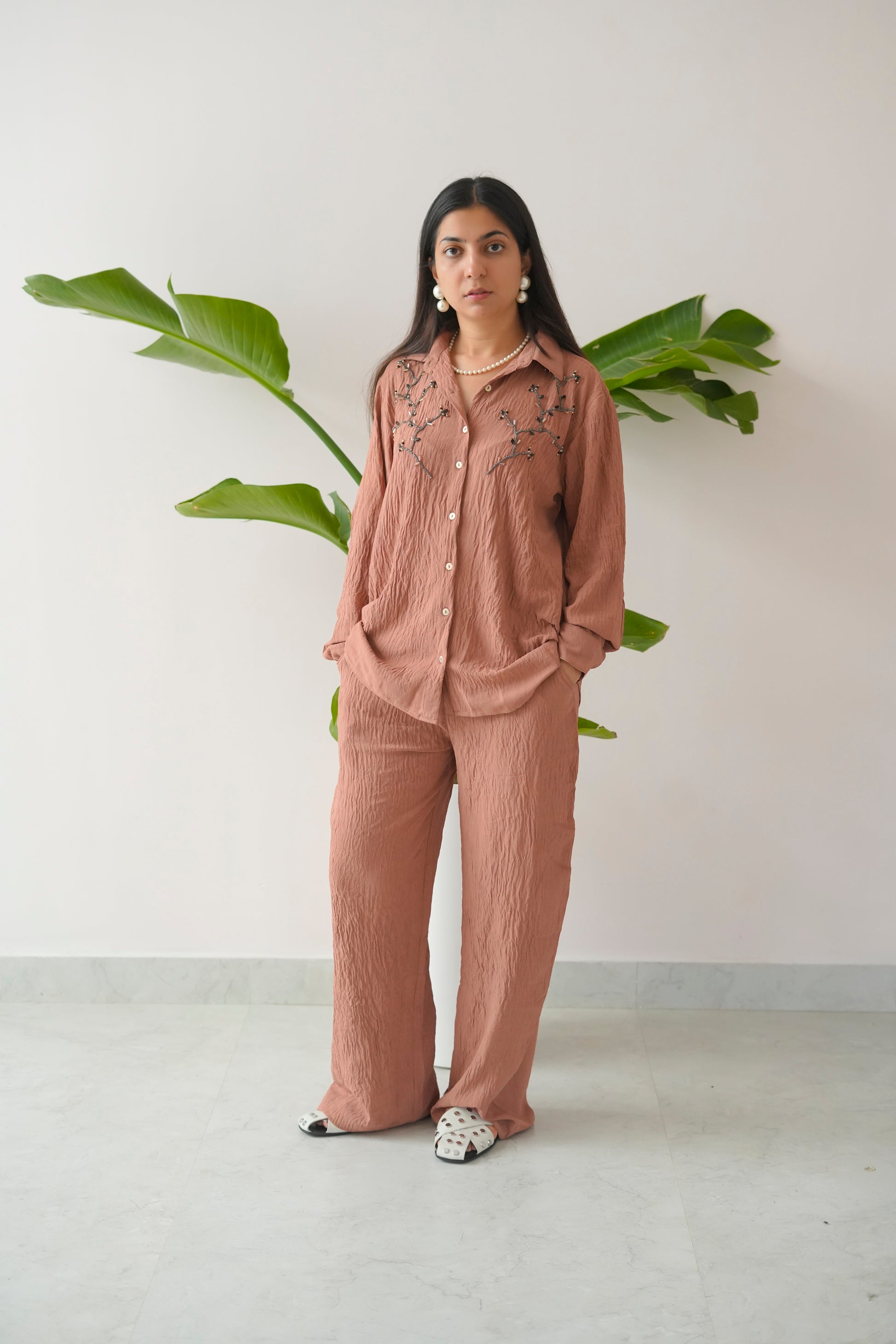 Woman wearing a pink outfit with a white background and green plant
