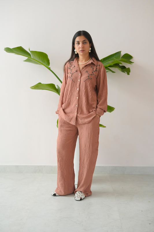 Woman wearing a pink outfit with a white background and green plant