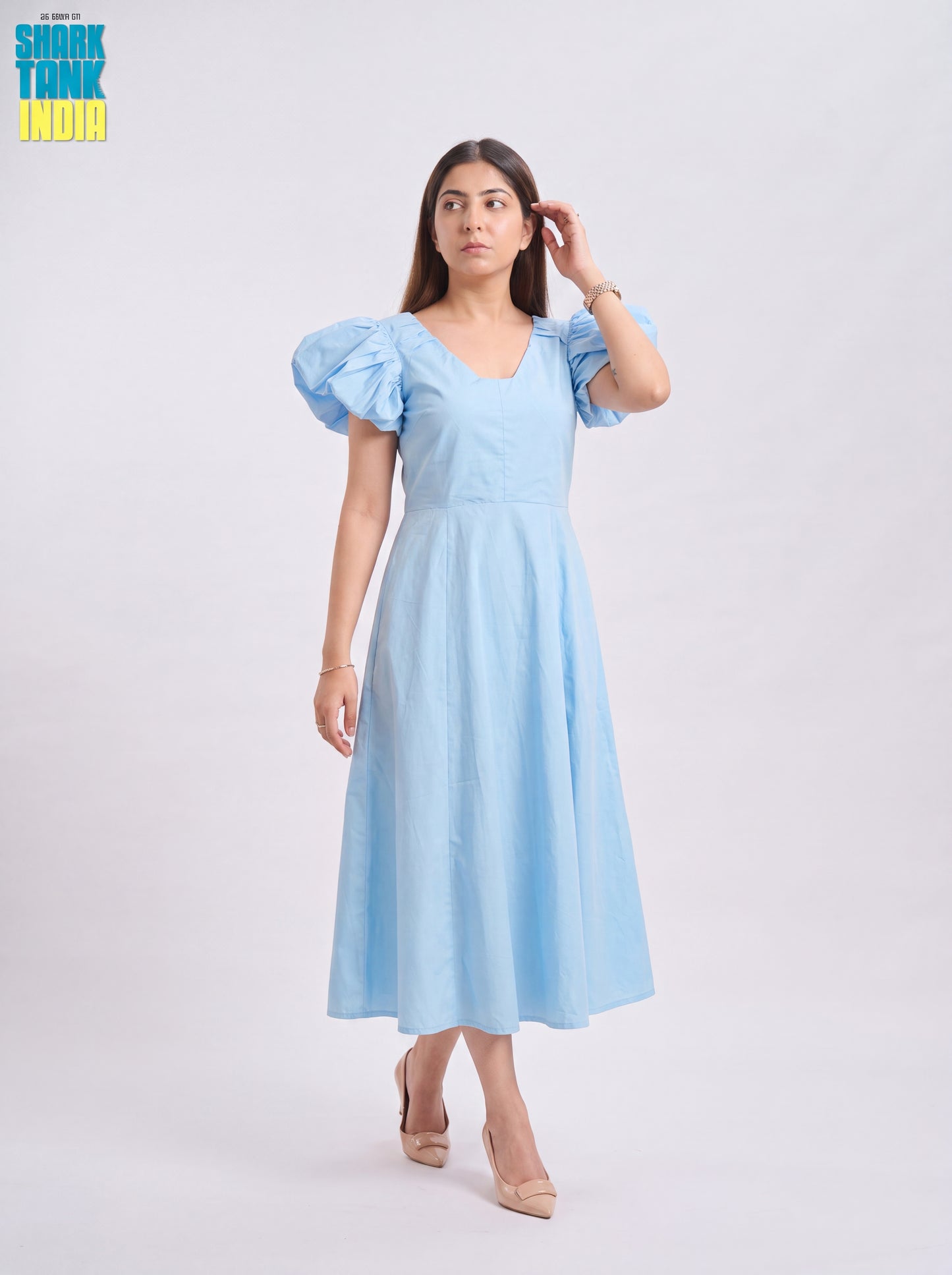 Woman wearing a light blue dress with puff sleeves on a white background