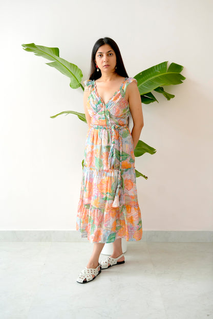Woman wearing a floral dress standing against a white wall with green leaves.