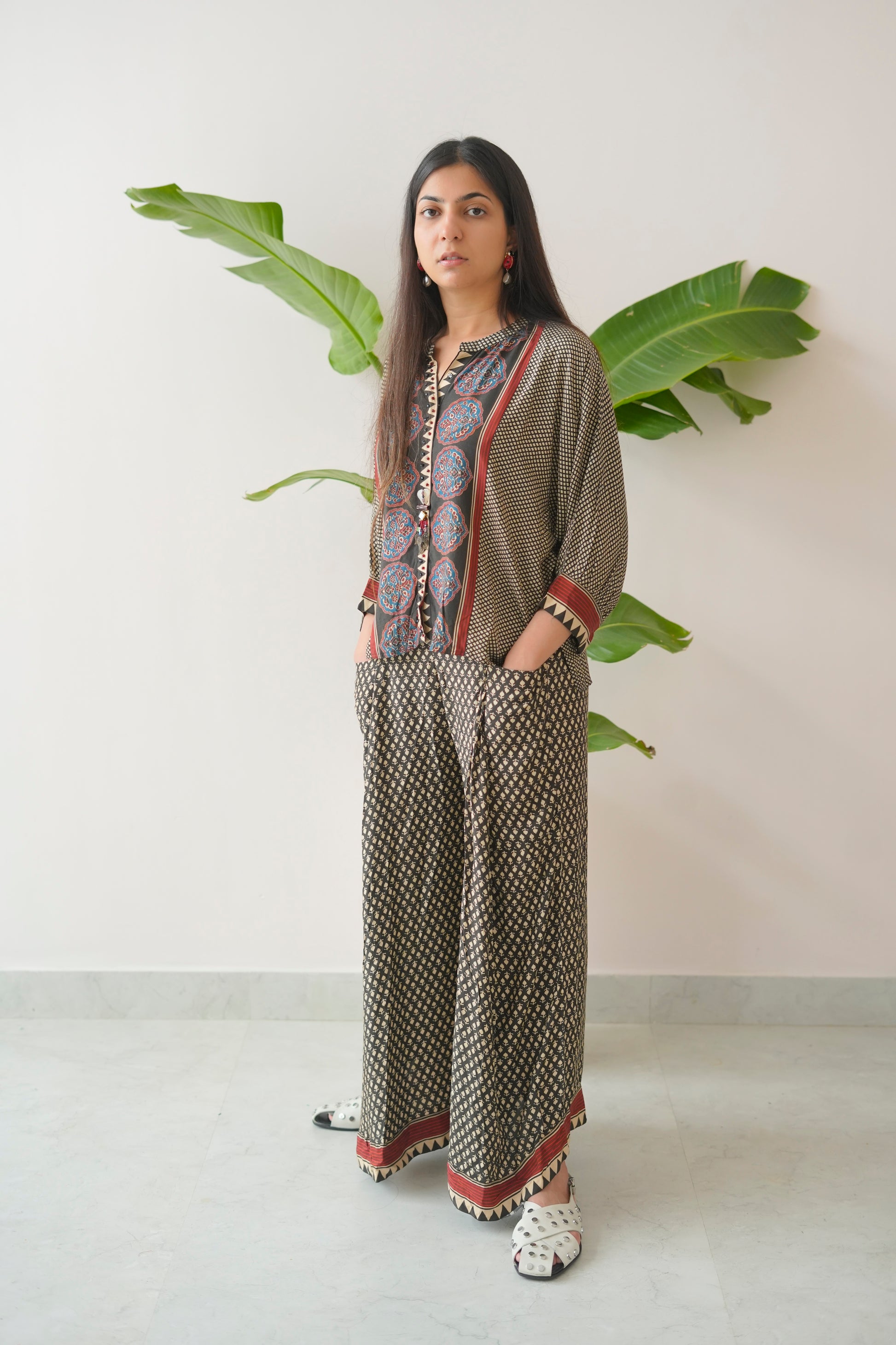 Woman wearing a patterned outfit with a plant in the background