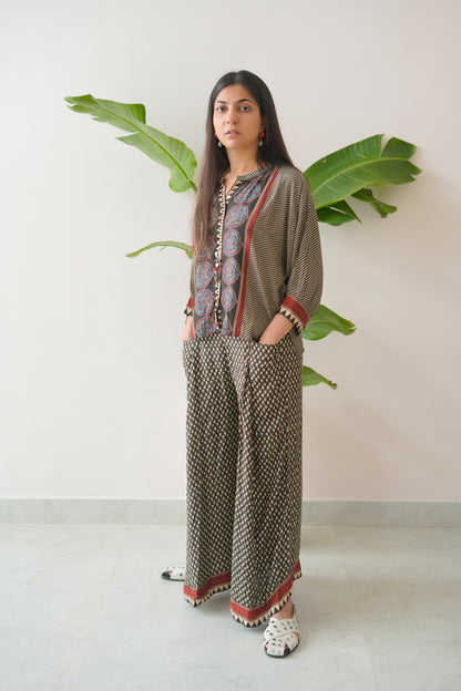 Woman wearing a patterned outfit with a plant in the background