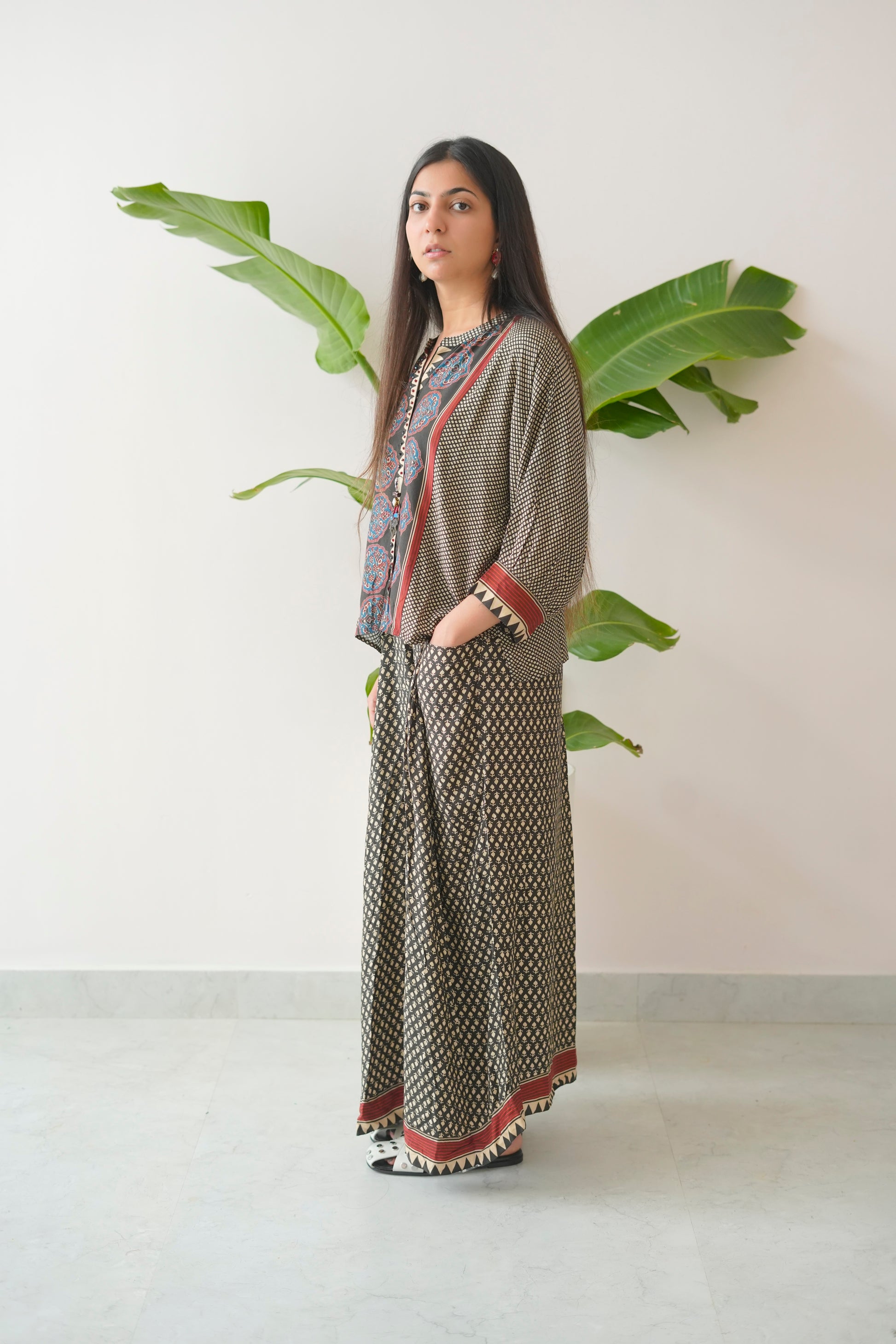 Woman wearing a patterned outfit with a plant in the background